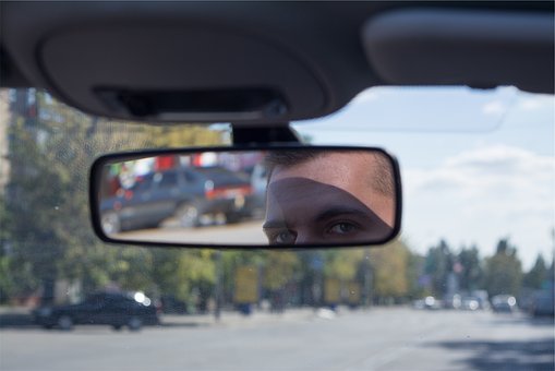 person looking in the rear view mirror inside a car